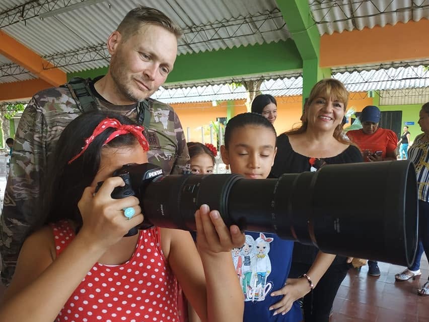 Niños miran por la Pentax y el teleobjetivo de Adam en un evento comunitario, enero de 2020
